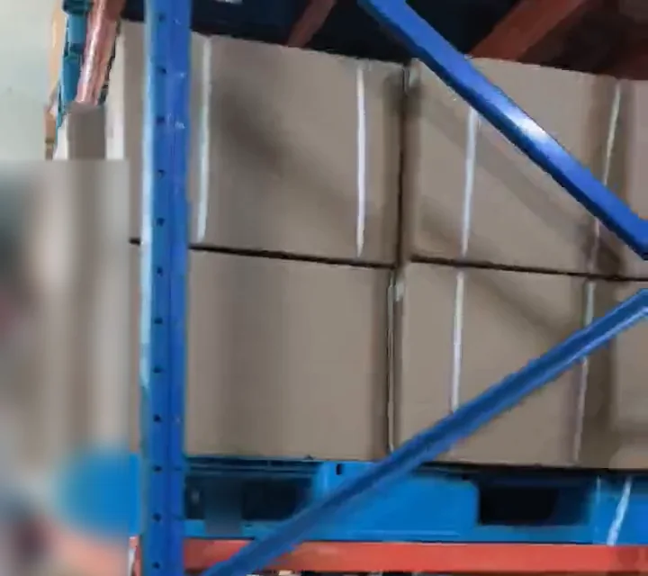 Stacked cartons behind blue and orange warehouse rack beams